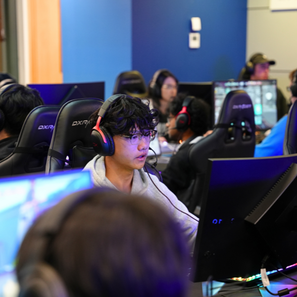 Student wearing headphones focused on a computer during an eSports gaming session at the Esport Arena, UoA.