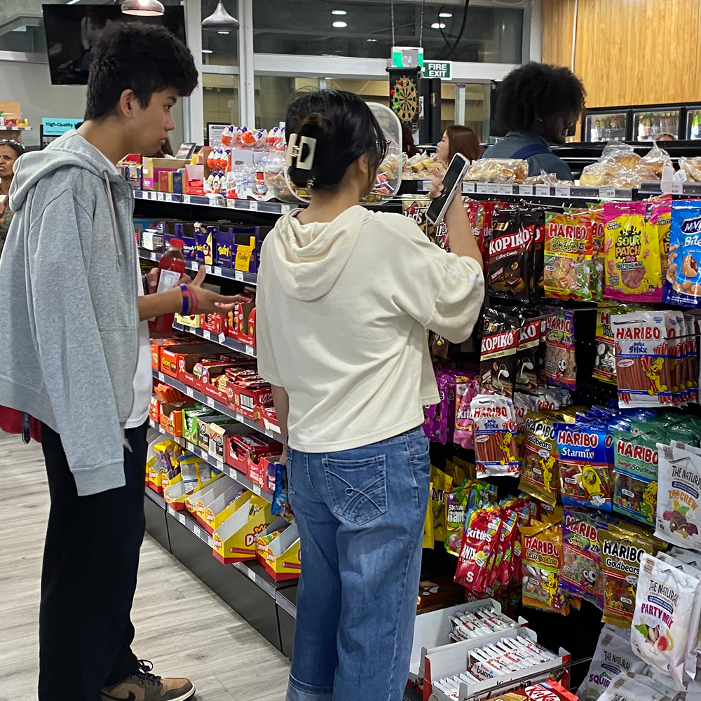 Two students inside Munchy Martlooking at the snack aisle