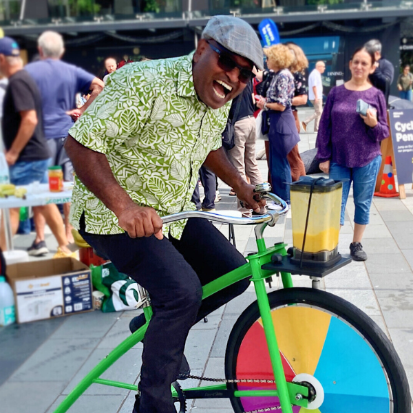 A person riding a green bike at an outdoor campus event